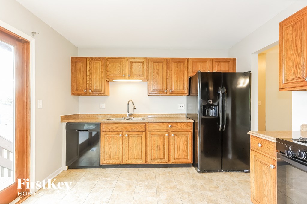 A kitchen with wooden cabinets and a black refrigerator.