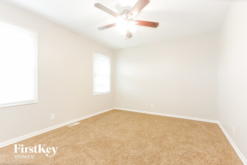 A room with a carpeted floor and a ceiling fan.