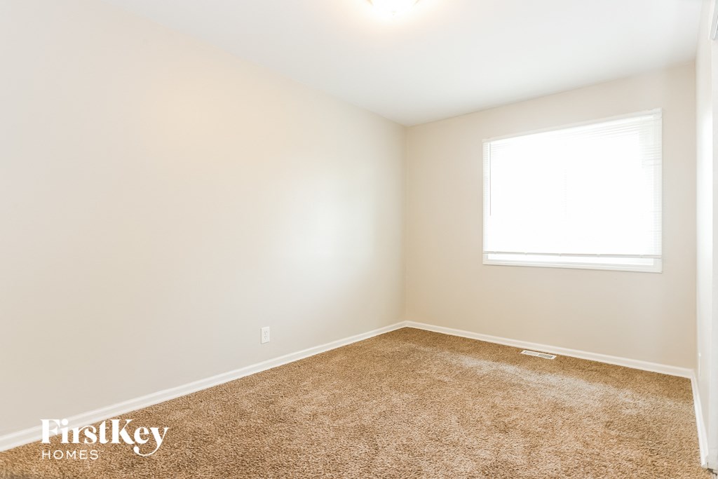 A carpeted room with a window and a FirstKey Homes logo.