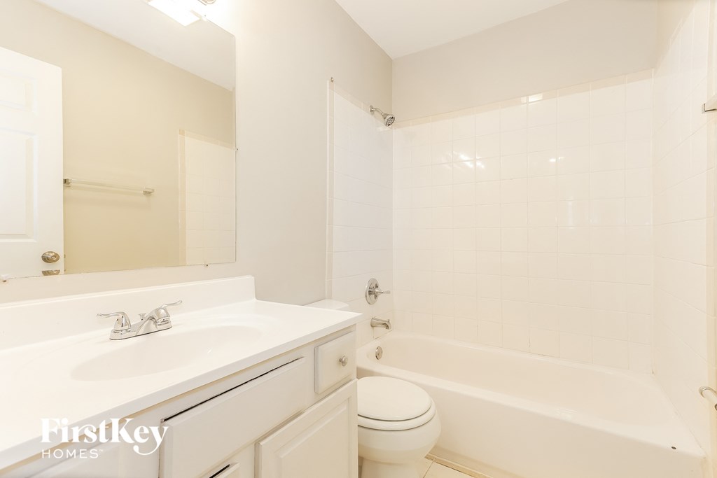 A white bathroom with a tub, sink and toilet.