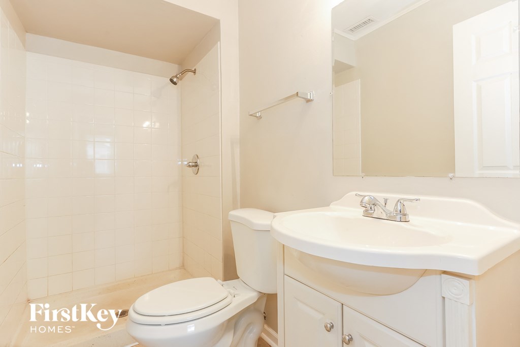 A white bathroom with a toilet, sink, and shower.