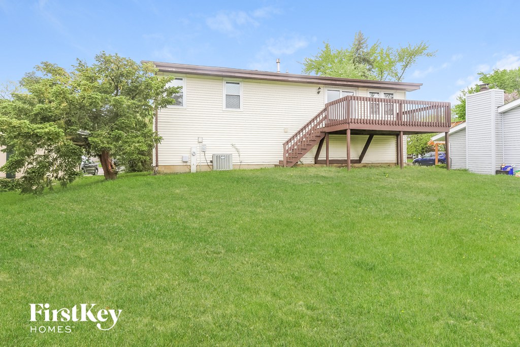 A house with a green lawn and a tree in front of it.