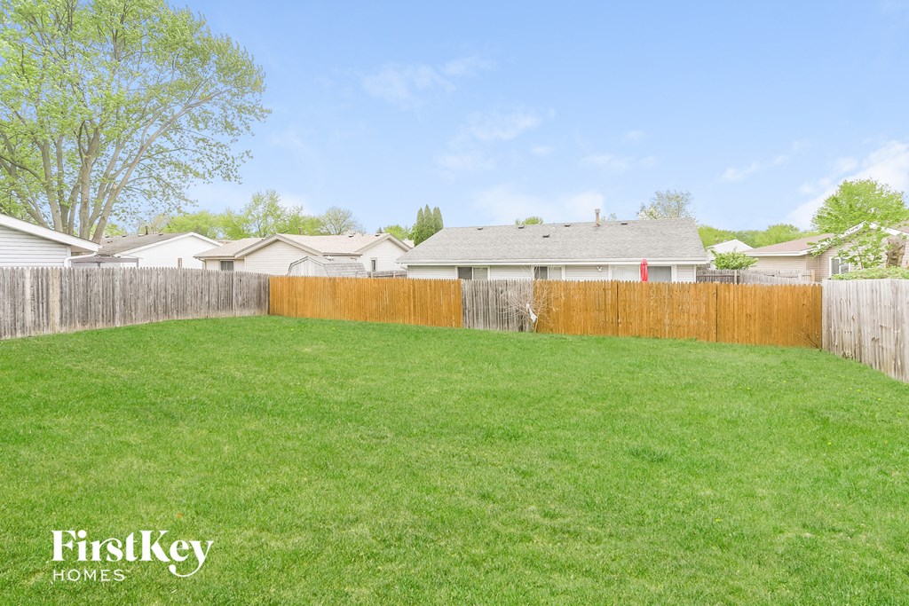 A backyard with a wooden fence and a green lawn.
