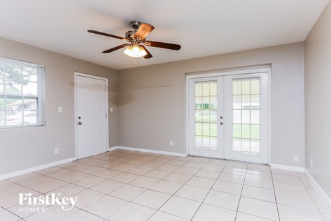 an empty living room with a ceiling fan and doors