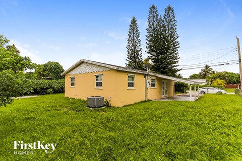 a yellow house on a hill with grass and trees