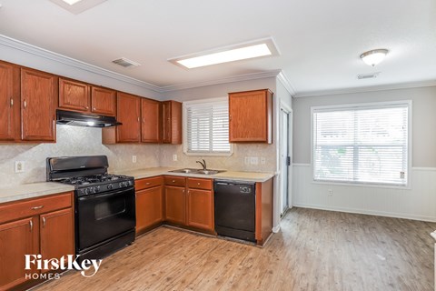 a kitchen with wood flooring and wooden cabinets and black appliances