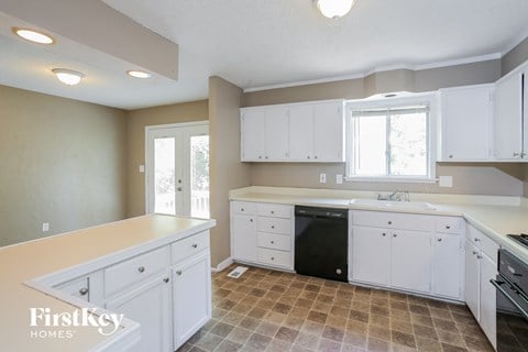 A kitchen with white cabinets and a tiled floor.