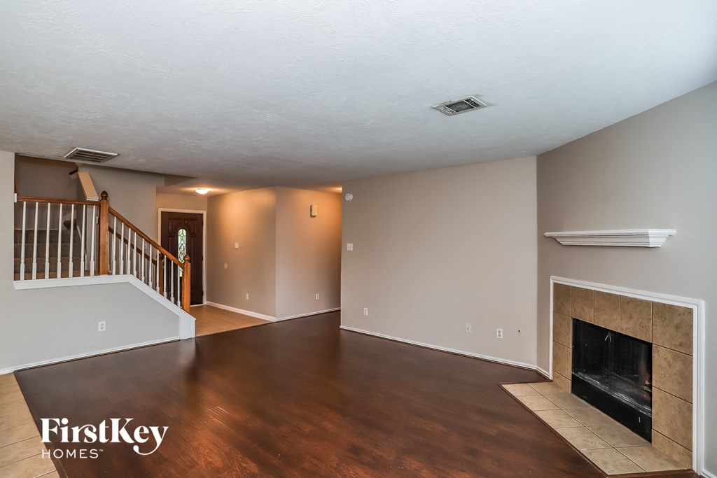 A spacious living room with a fireplace and a staircase.