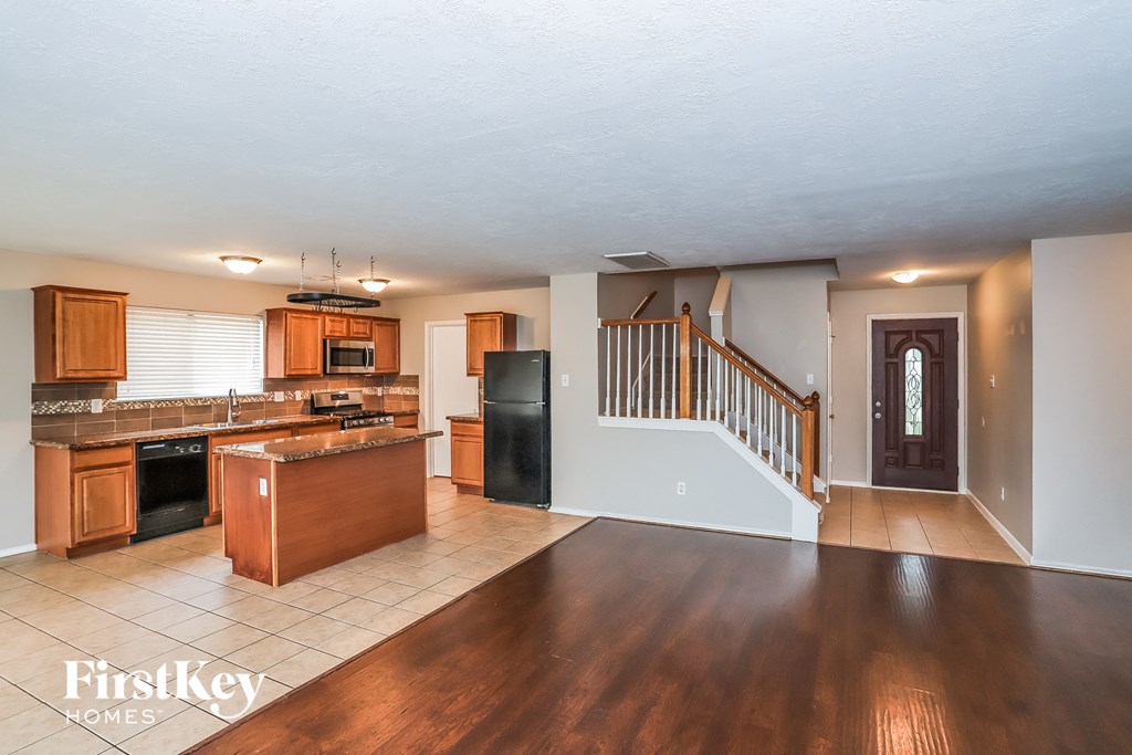 A spacious kitchen with wooden floors and a staircase.