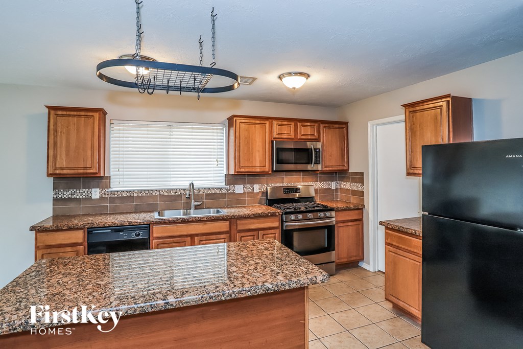 A kitchen with granite countertops and wooden cabinets.