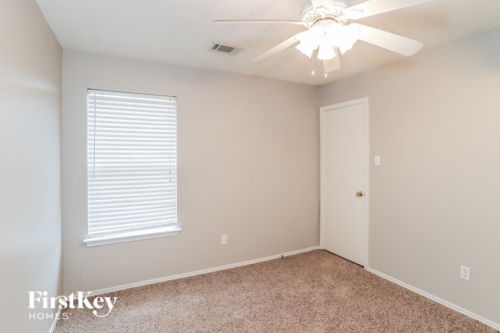 A room with a ceiling fan and a window with blinds.