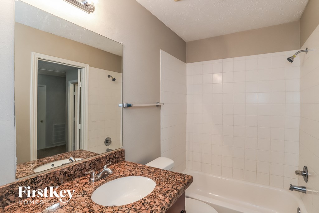 A bathroom with a marble countertop and a white sink.