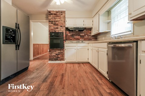A kitchen with wooden floors and a brick chimney.