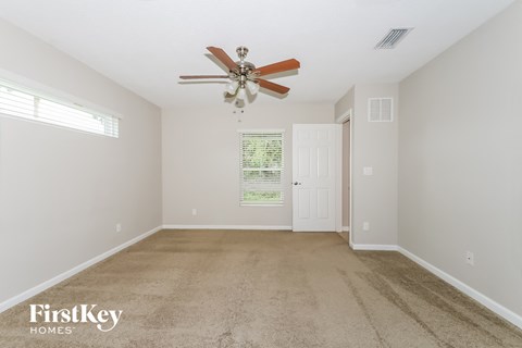 a spacious living room with carpet and a ceiling fan