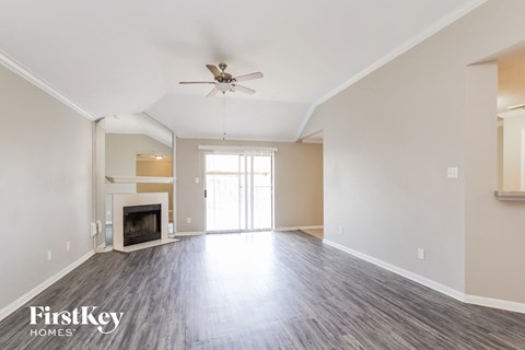 A spacious living room with a fireplace and a ceiling fan.