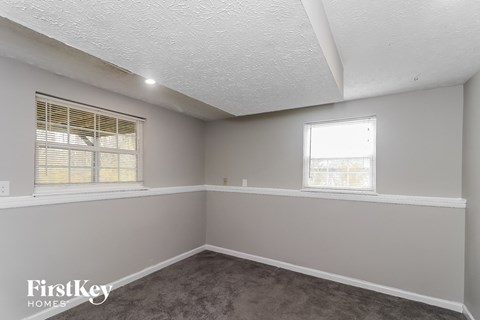 the living room of a house with two windows and a carpet