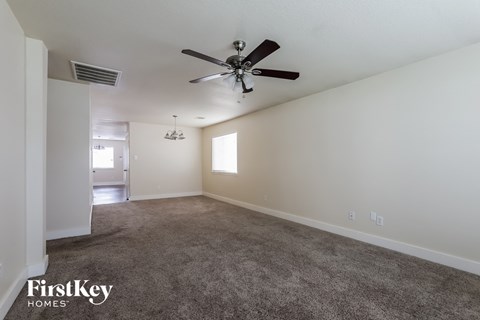 A spacious room with a ceiling fan and carpeted floor.