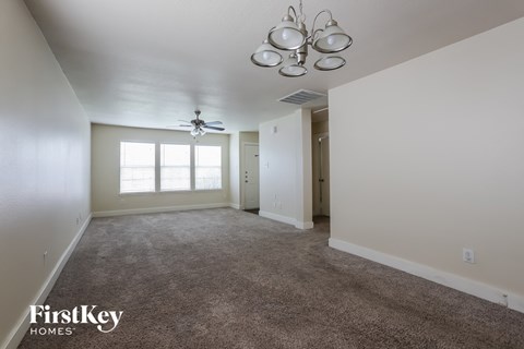 A spacious room with a carpeted floor and a ceiling fan.