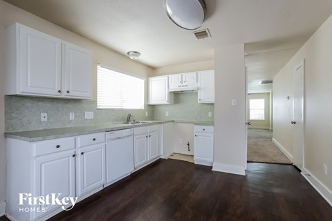 A kitchen with white cabinets and a wooden floor.