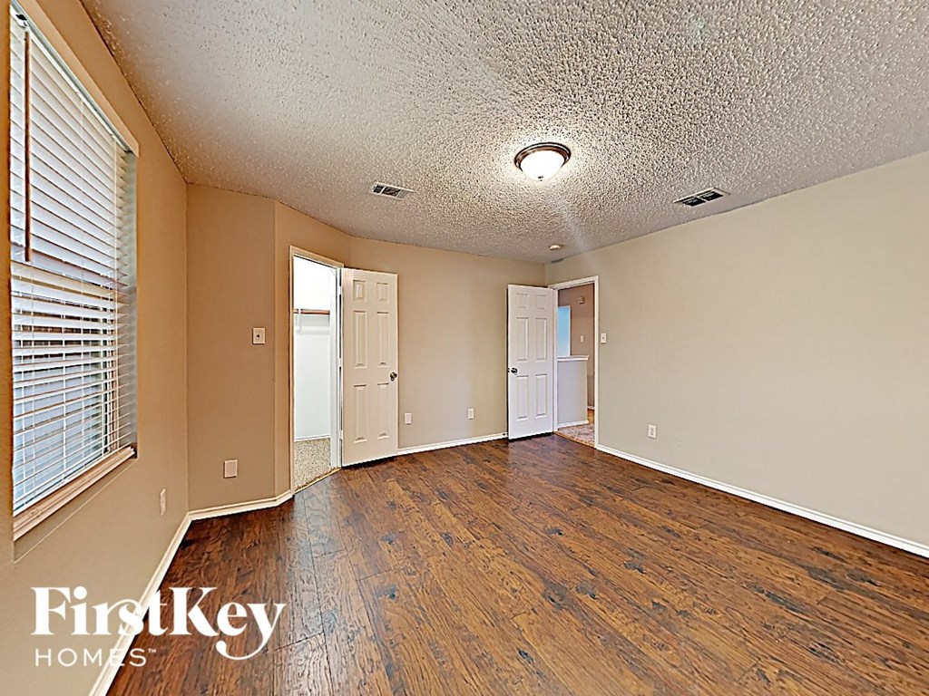 an empty living room with wood flooring and a window