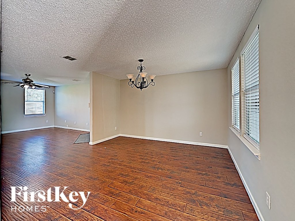 an empty living room with wood floors and a chandelier
