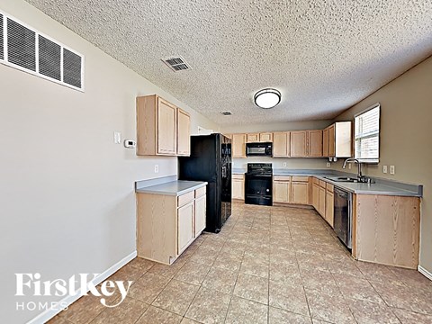 a kitchen with wood cabinets and a black refrigerator