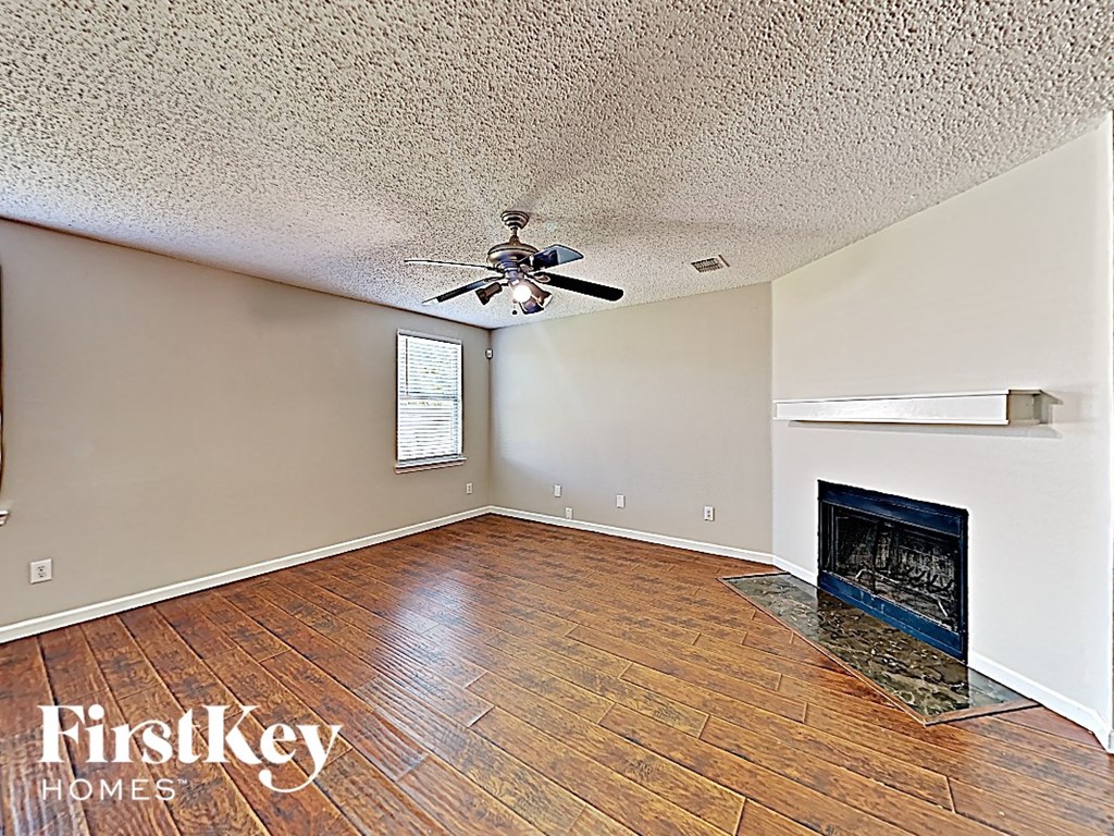an empty living room with a fireplace and a ceiling fan