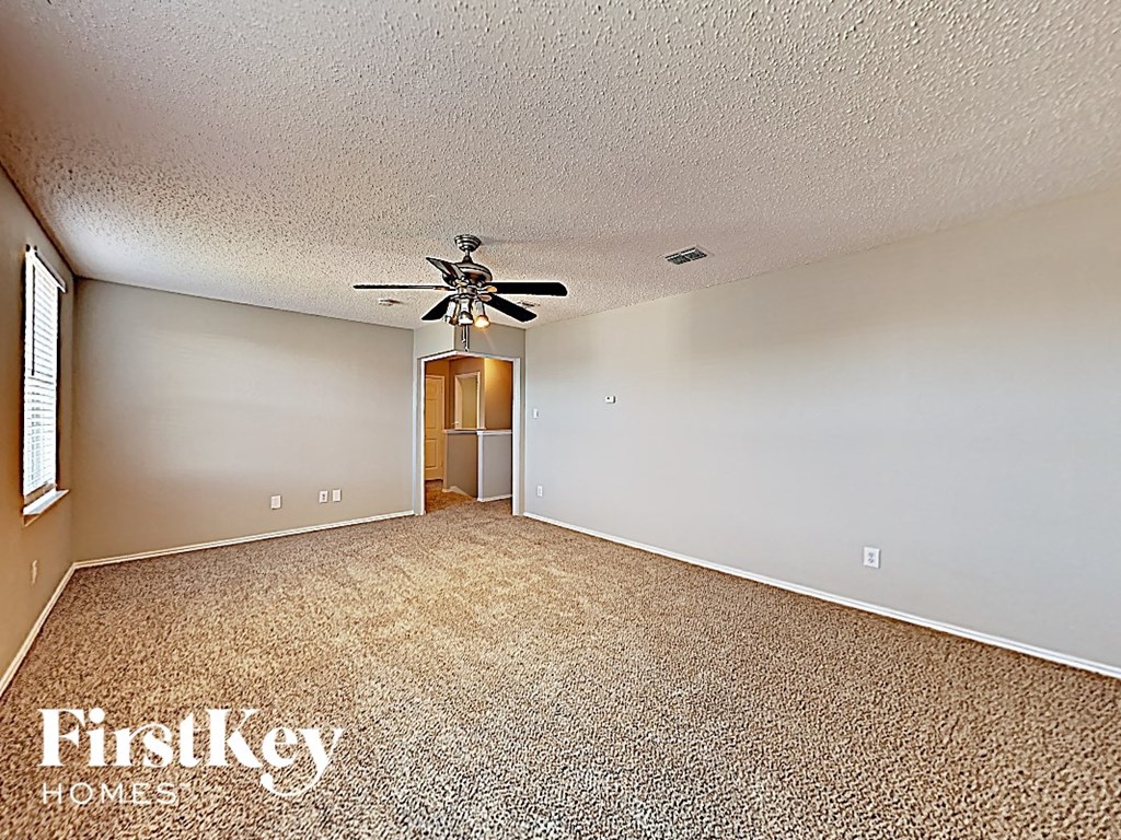 an empty living room with a ceiling fan