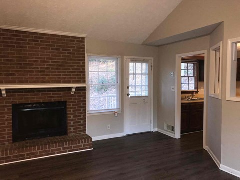 a living room with a brick fireplace and a door to a bathroom