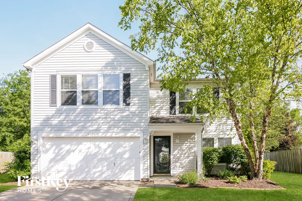 a white house with a white garage door and a tree