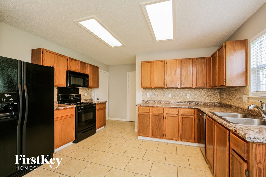 a kitchen with wooden cabinets and black appliances and a sink