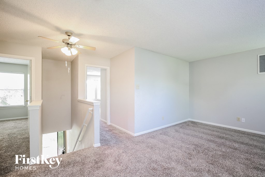 an empty living room with carpet and a ceiling fan