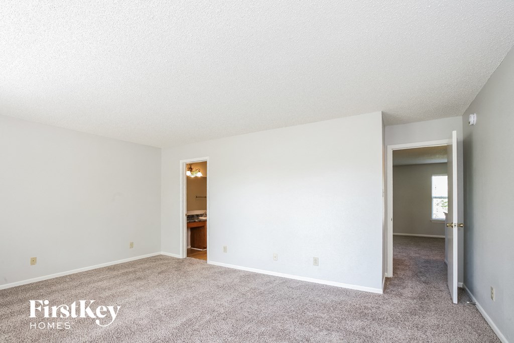 an empty living room with carpet and a door to a bathroom