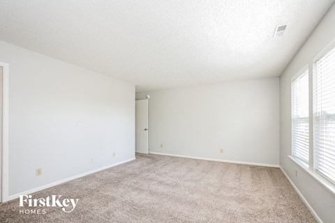 a spacious living room with carpet and large windows