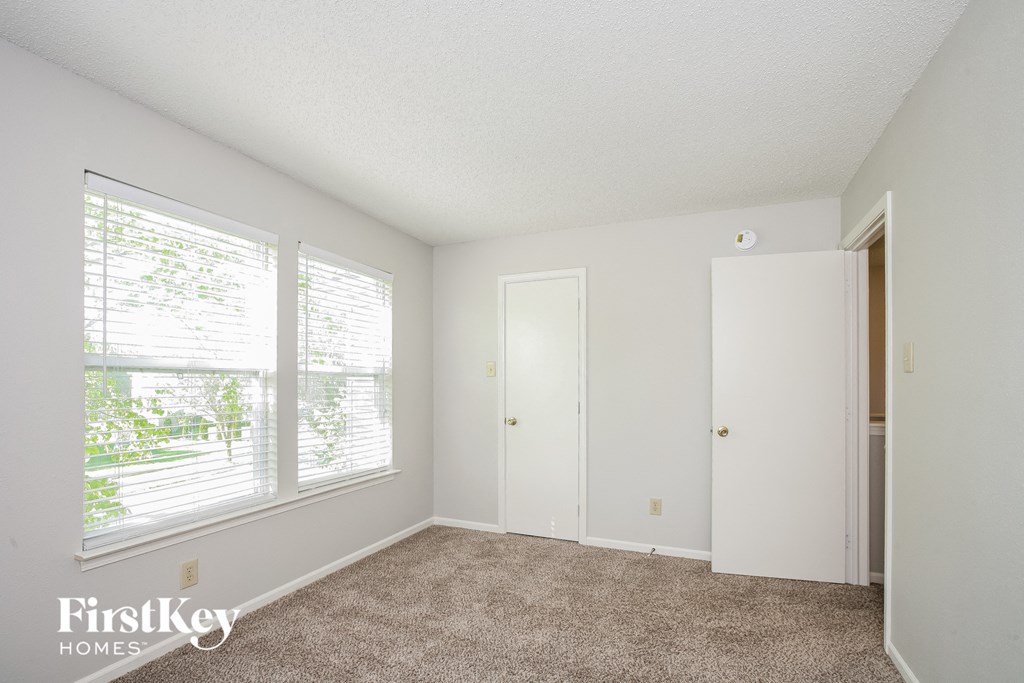 a bedroom with a large window and a carpeted floor
