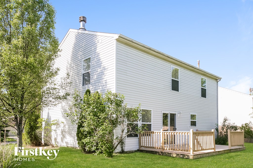 a white house with a deck and a tree