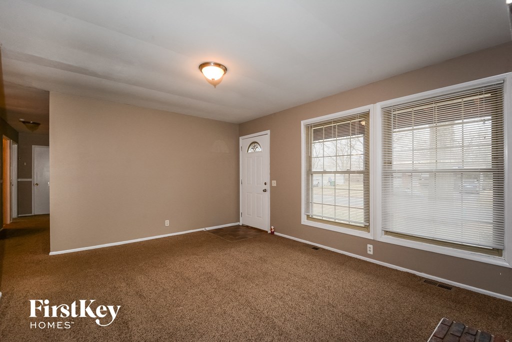 an empty living room with two windows and a door