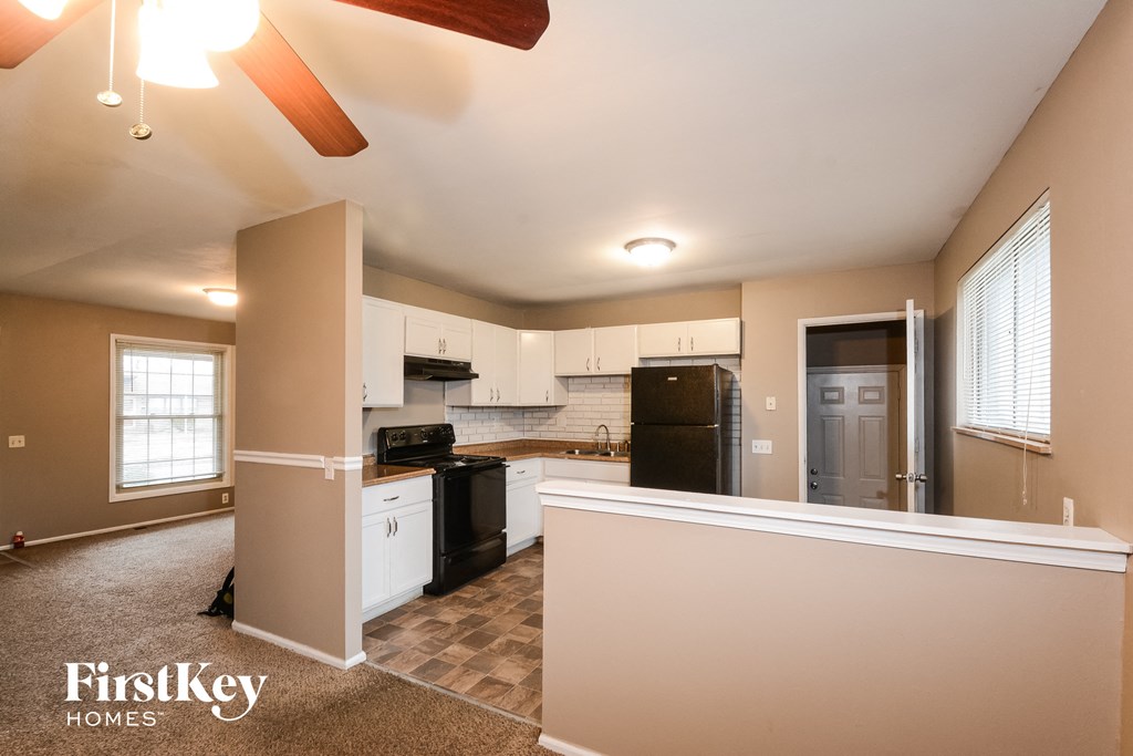 a kitchen with white cabinets and a black refrigerator