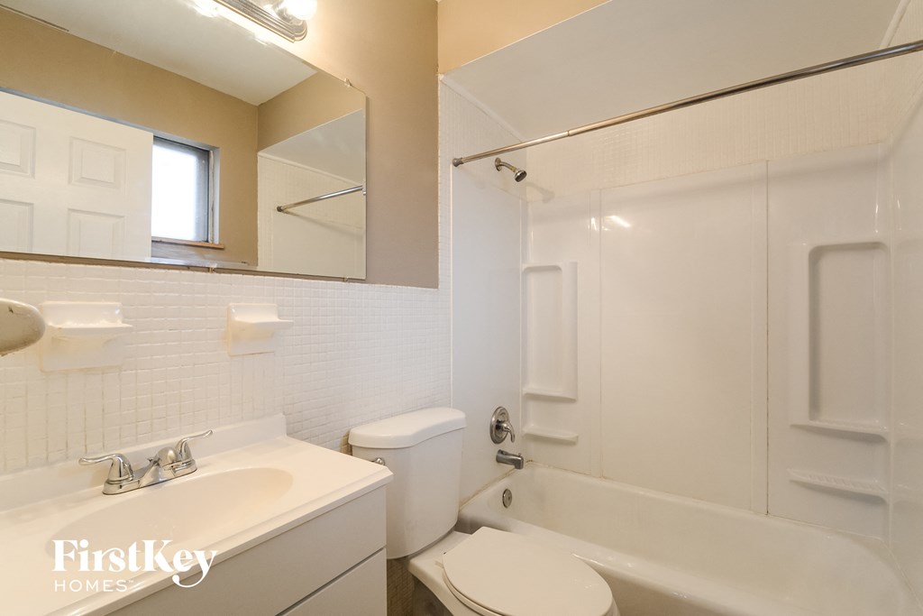 a white bathroom with a tub and a sink and a toilet