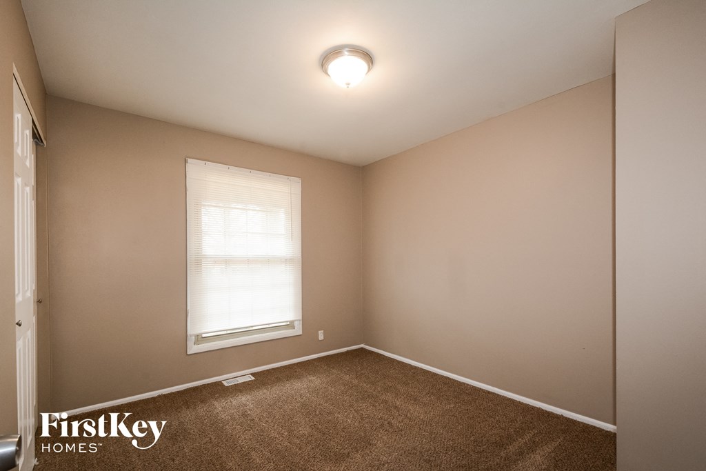 the bedroom of a house with a window and a carpet