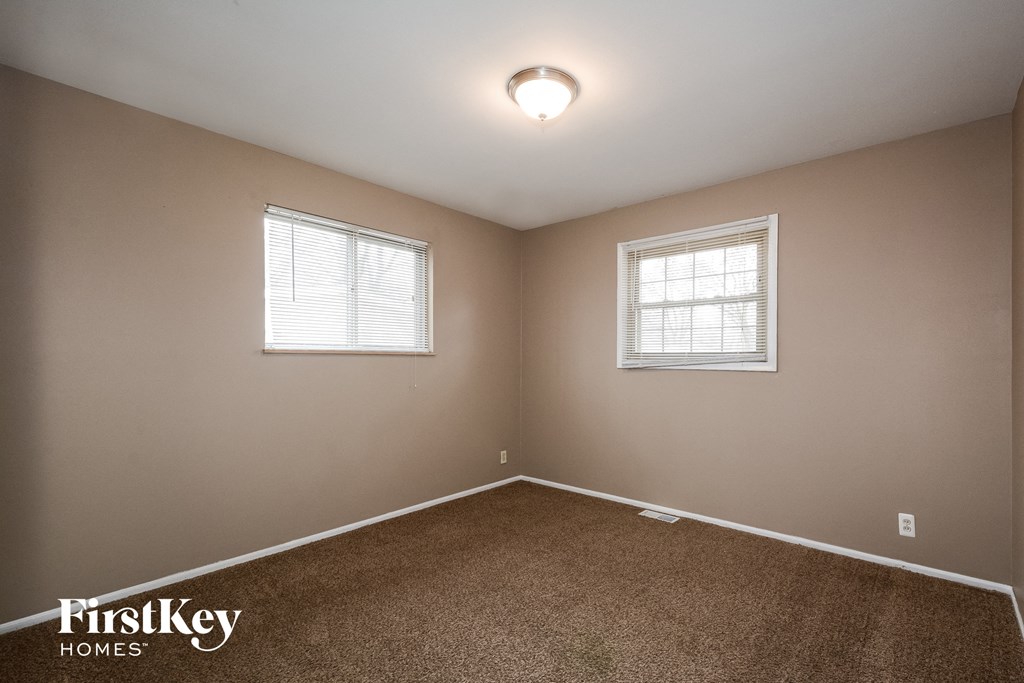 a bedroom with two windows and a carpeted floor