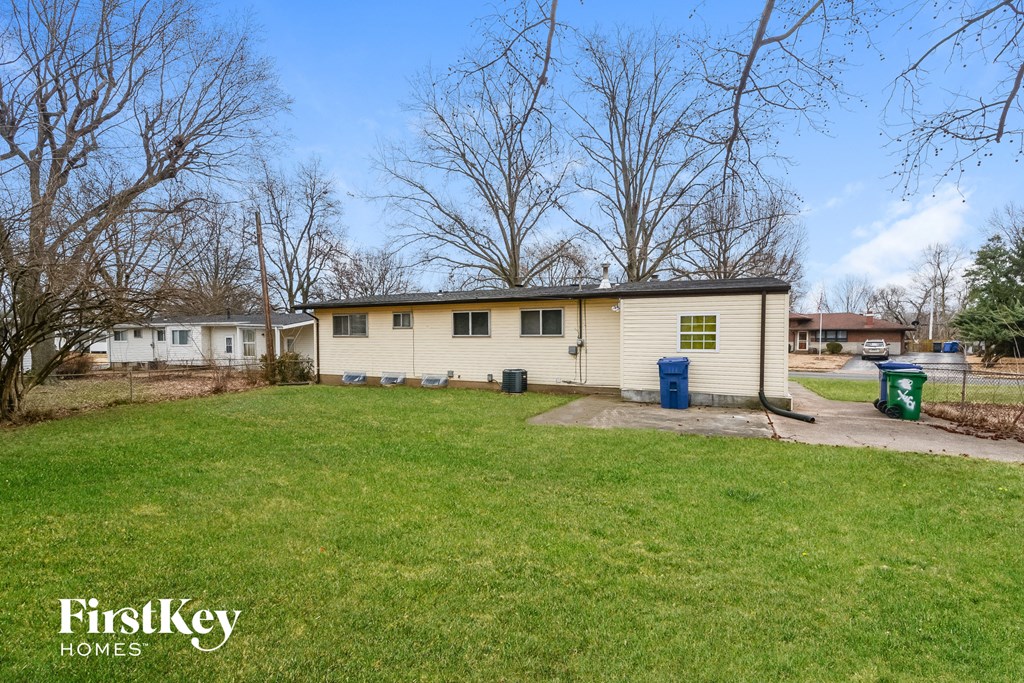 a small yellow house with a yard and some trees