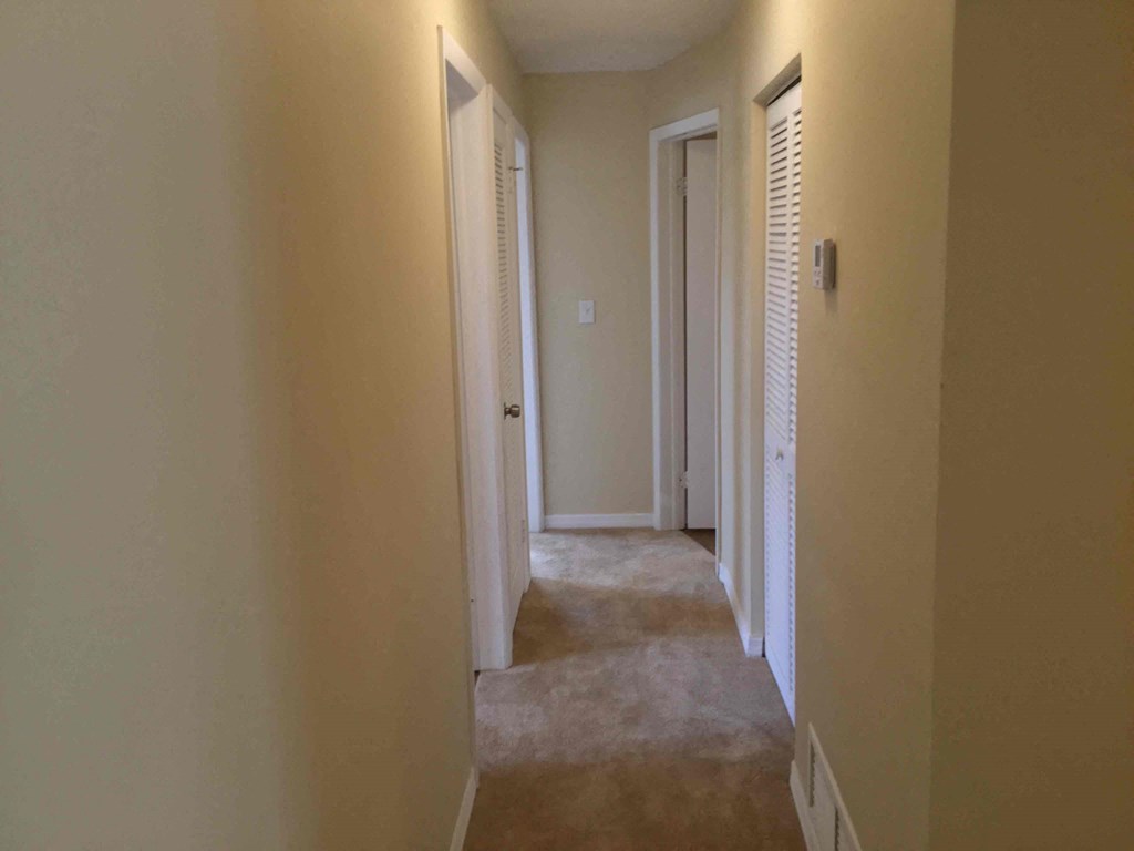 a hallway with a carpeted floor and white walls and doors