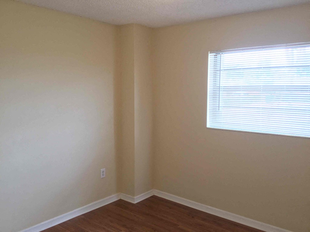 a corner of a room with a window and a wooden floor