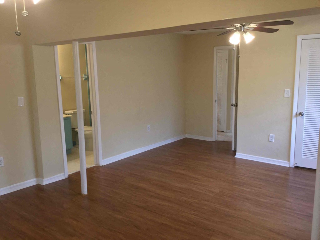 an empty living room with wood floors and a ceiling fan