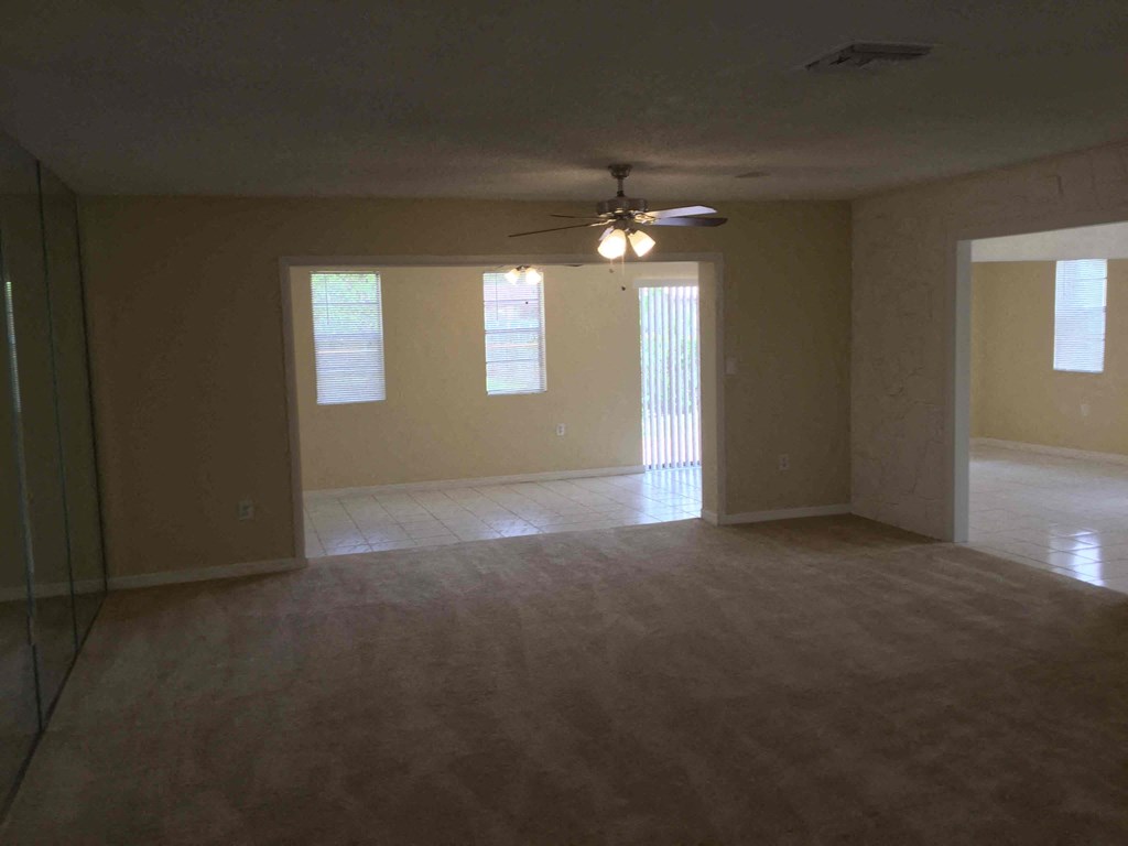 an empty living room with a ceiling fan