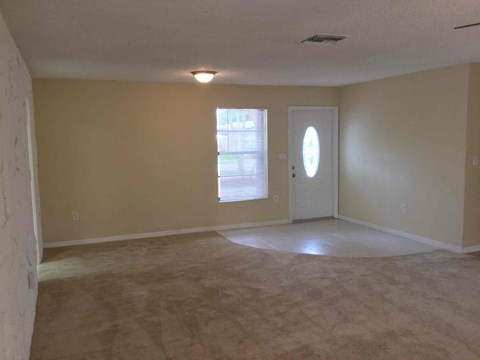 an empty living room with beige walls and a white door