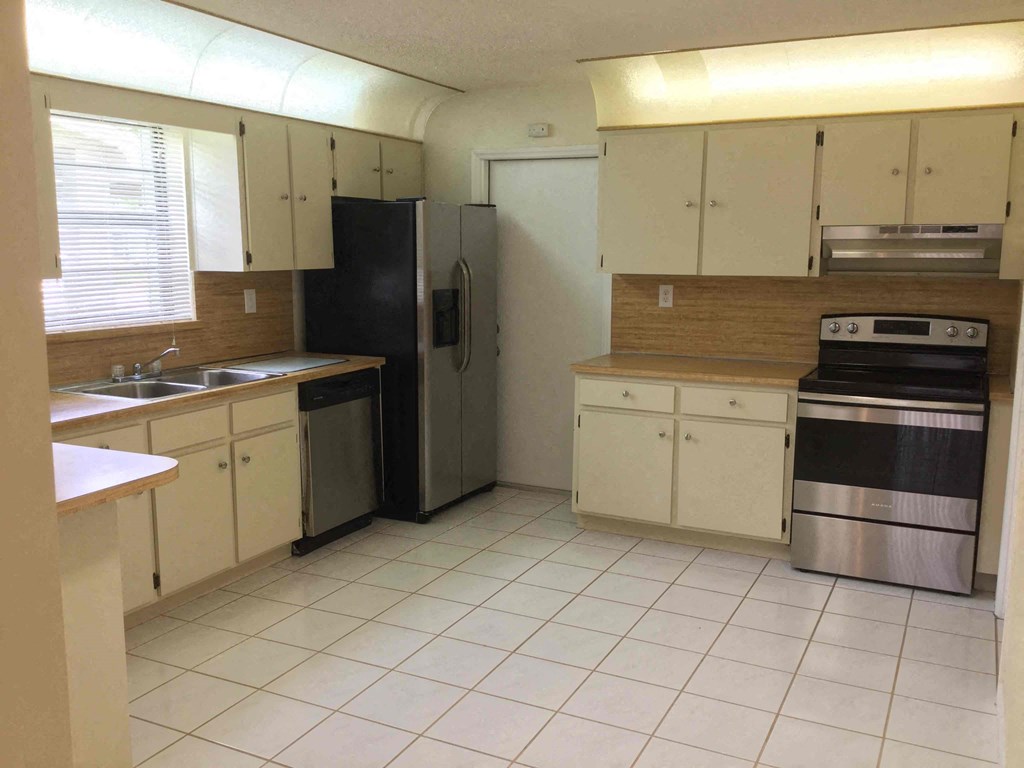 an empty kitchen with a stove refrigerator and sink