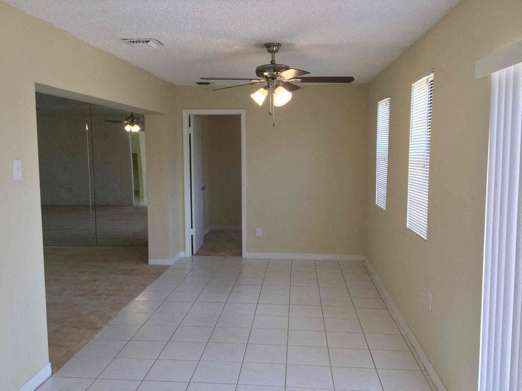an empty living room with a ceiling fan and a tiled floor