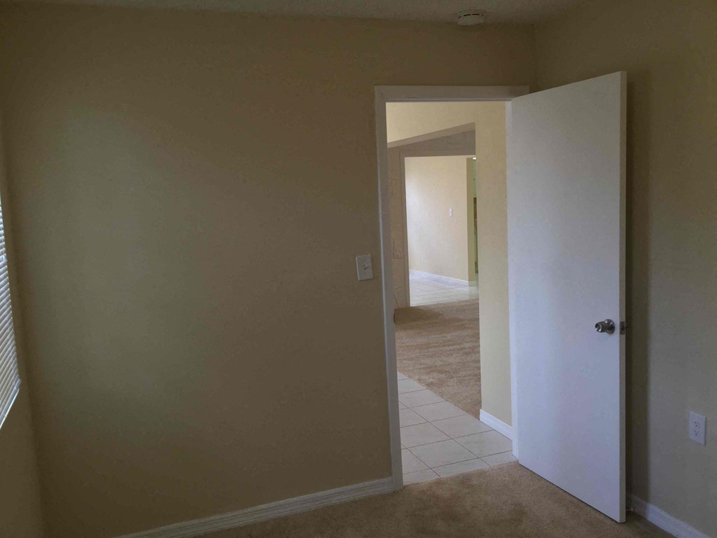 a room with a door open to a hallway and a door to a bedroom